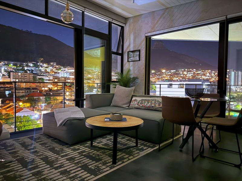 The living room at One26 on M at night, Sea Point lit up below